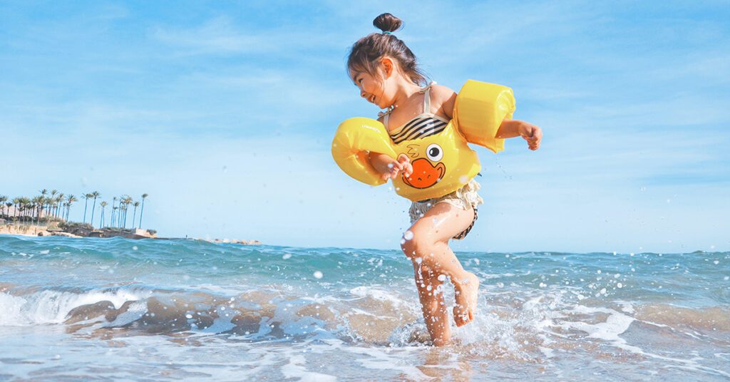 Un enfant avec des brassards au bord de la mer à la plage