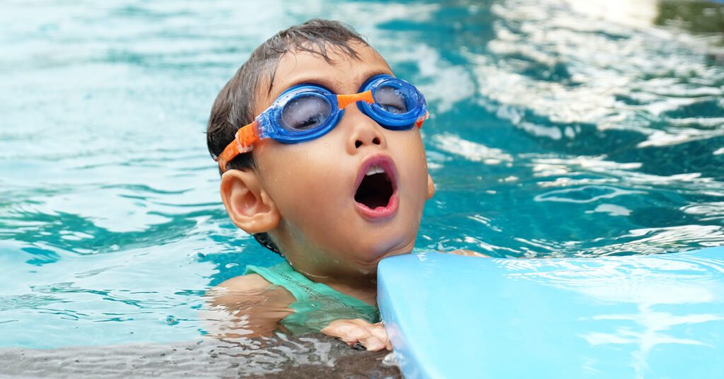 Un enfant avec des lunettes de piscine jouant dans l'eau