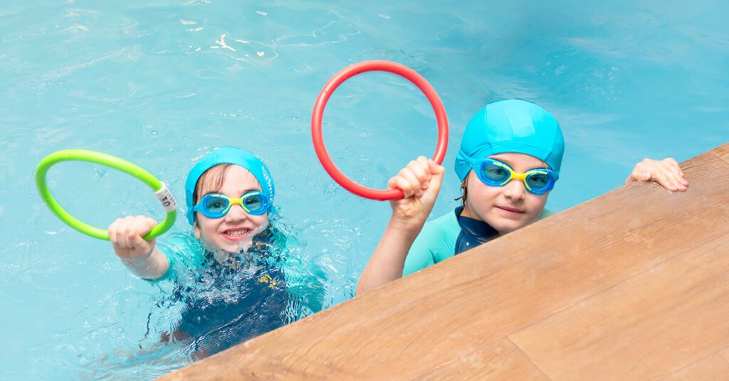 Deux enfants dans un bassin avec des petits cerceaux en main