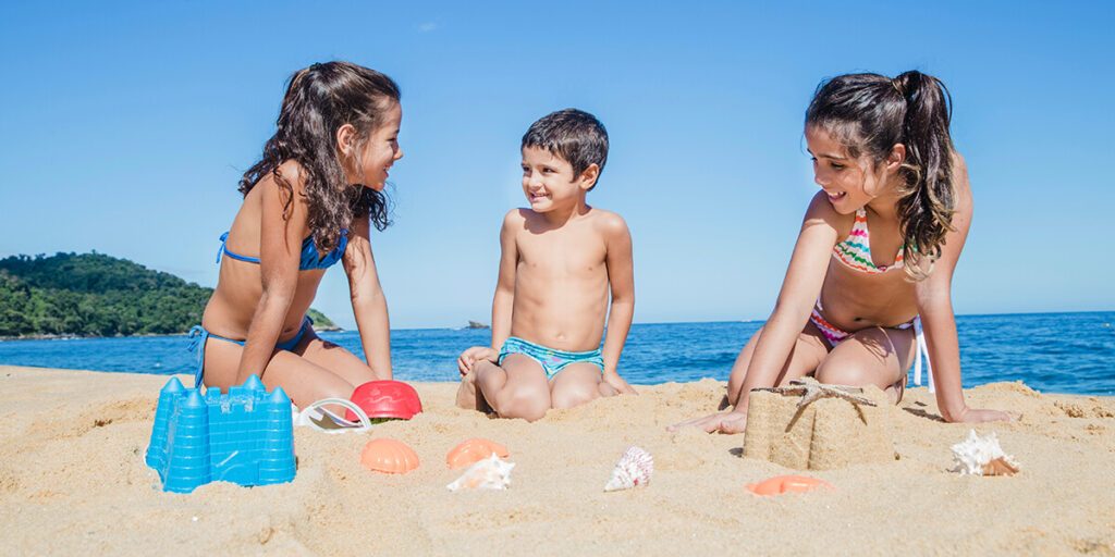 3 enfants qui s'amusent dans le sable sur la plage