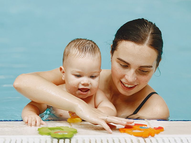 Un bébé qui s'amuse au bord de la piscine avec sa maman