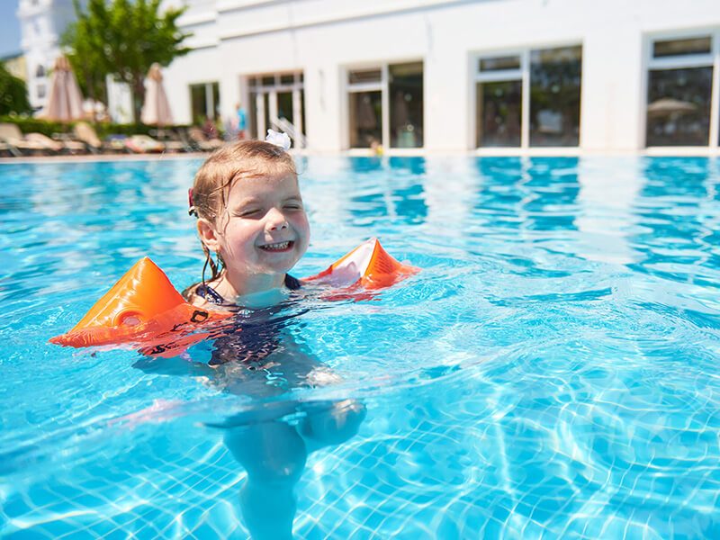 Une petite fille qui s'amuse dans l'eau avec des brassards