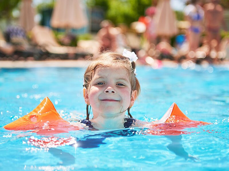 Une petite fille qui se baigne dans une piscine avec des brassards