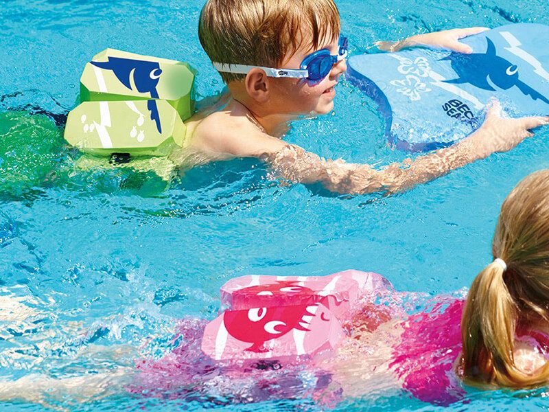 Une fille et un garçon qui nage dans une piscine avec une ceinture de natation