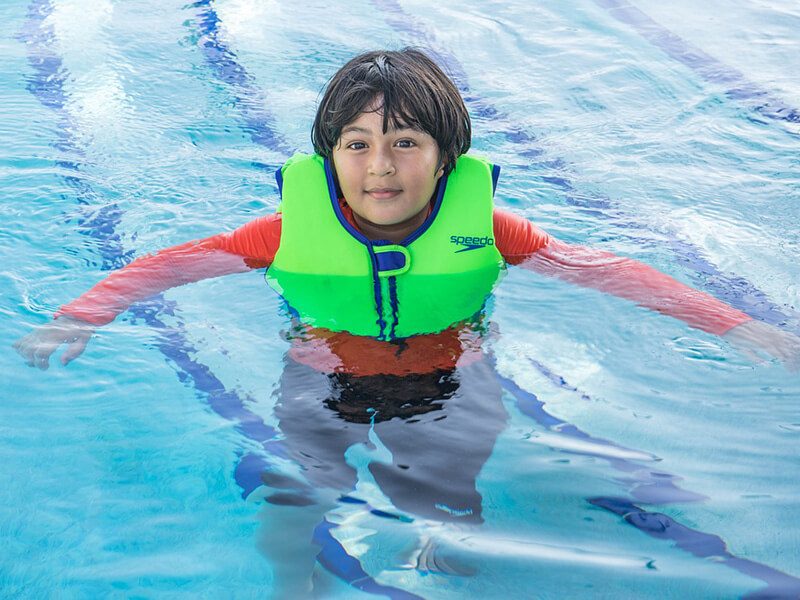 Un enfant qui se baigne dans une piscine avec un gilet de natation