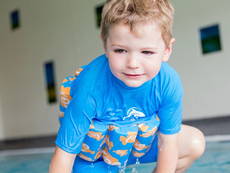 Un petit garçon dans une piscine avec un maillot flotteur