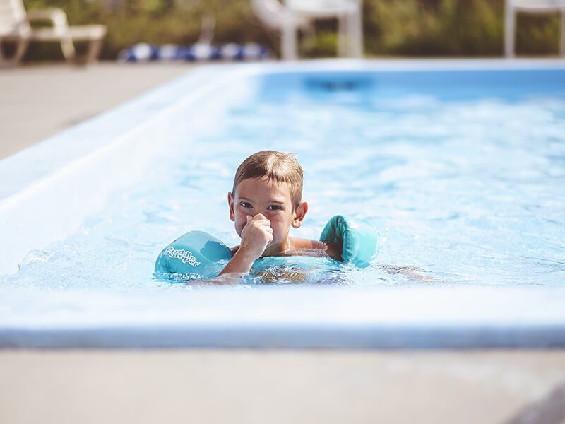 Un garçon qui se baigne dans une piscine avec un puddle jumper