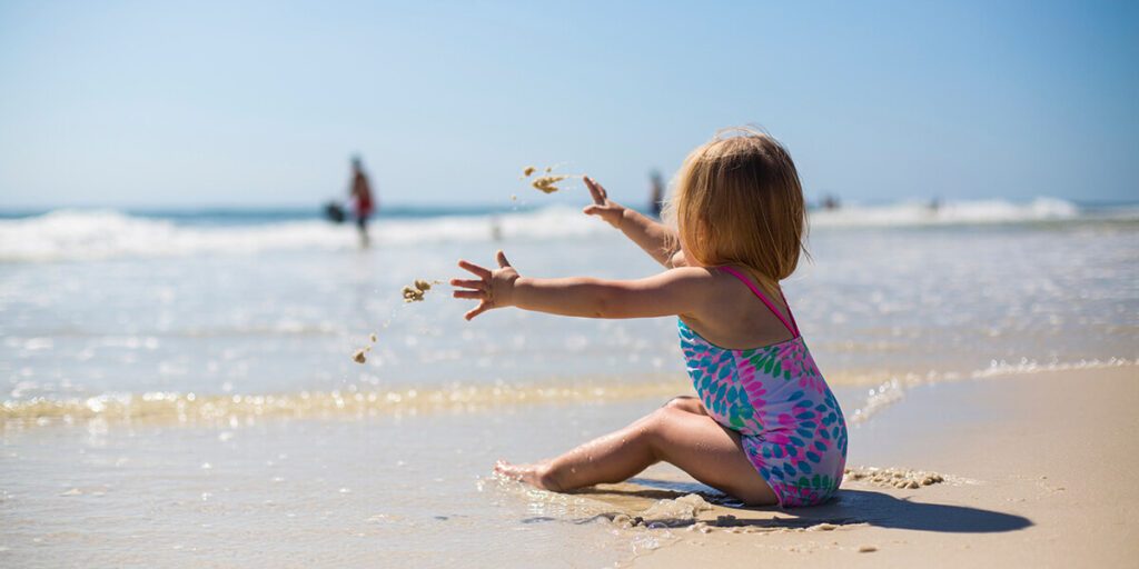 Un bébé qui s'amuse dans le sable au bord de l'eau à la plage