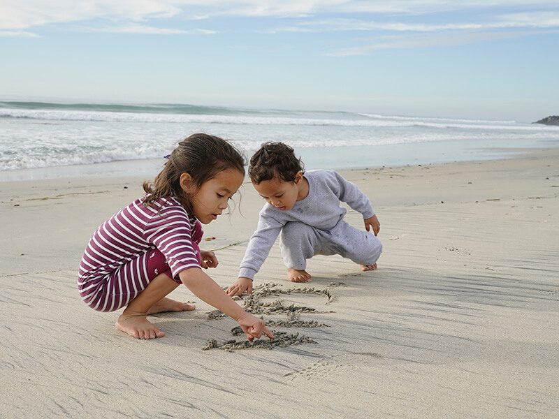 Deux bébés en train de jouer avec le sable sur la plage