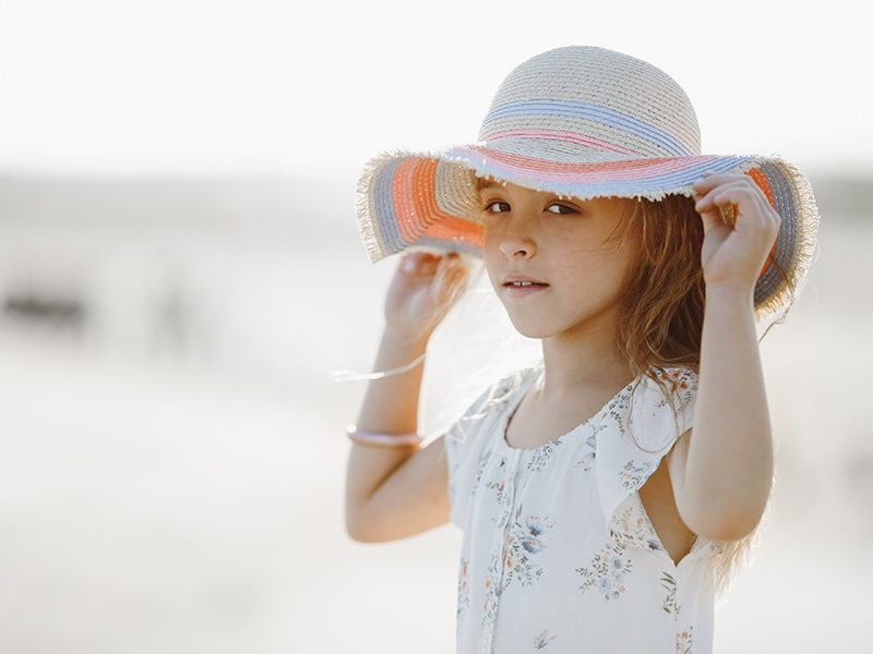 Une petite fille à la plage avec un chapeau sur la tête