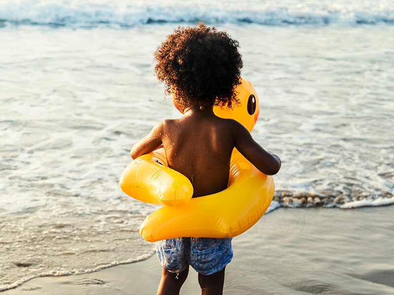 Un bébé avec une bouée au bord de la mer