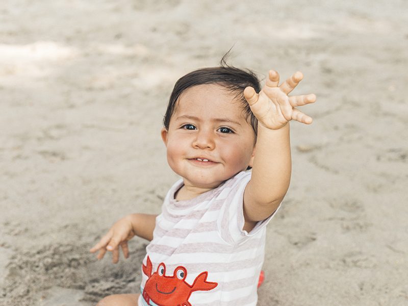 Un bébé à la plage qui s'amuse sur le sable