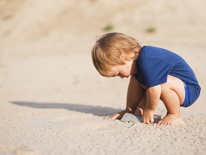 Un bébé qui s'amuse avec du sable sur la plage