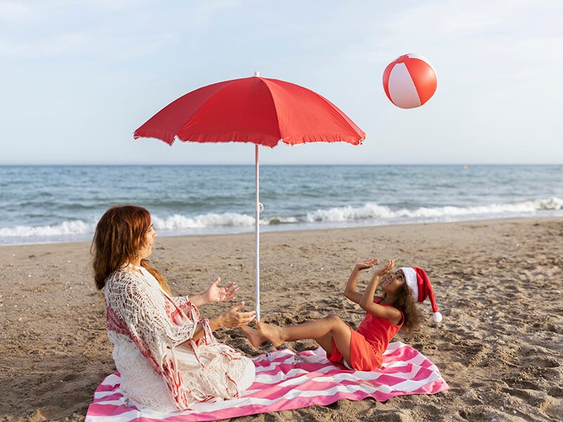 Une mère et sa fille sous un parasol à la plage