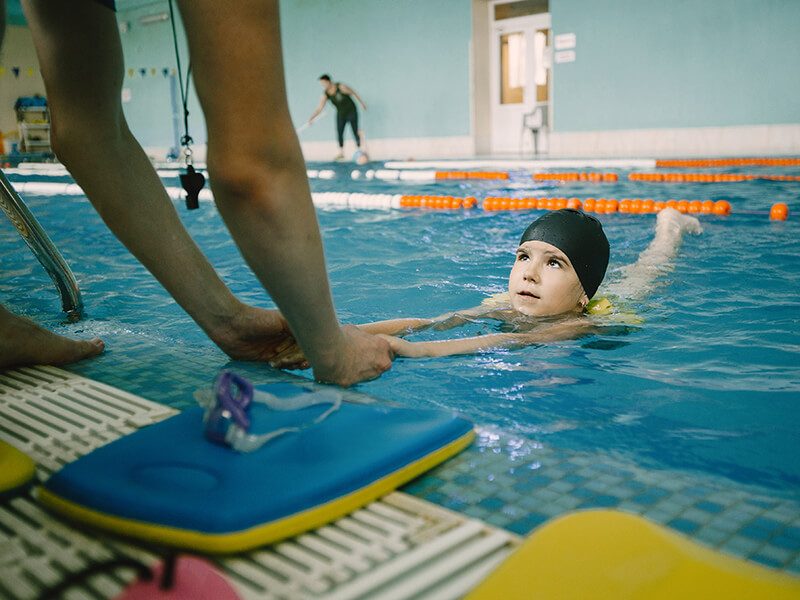 Un maitre-nageur qui apprend à un enfant à nager en le tenant par les bras