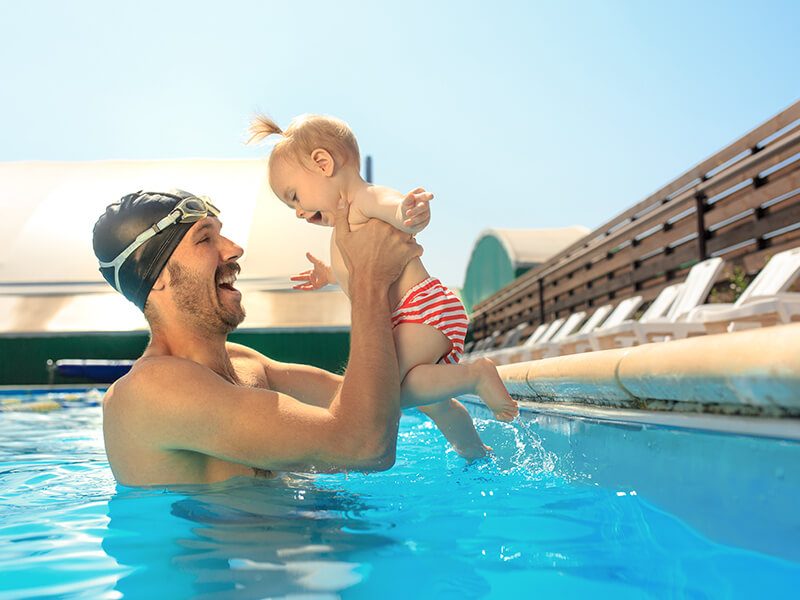 Un papa qui tient son bébé dans les bras dans une piscine