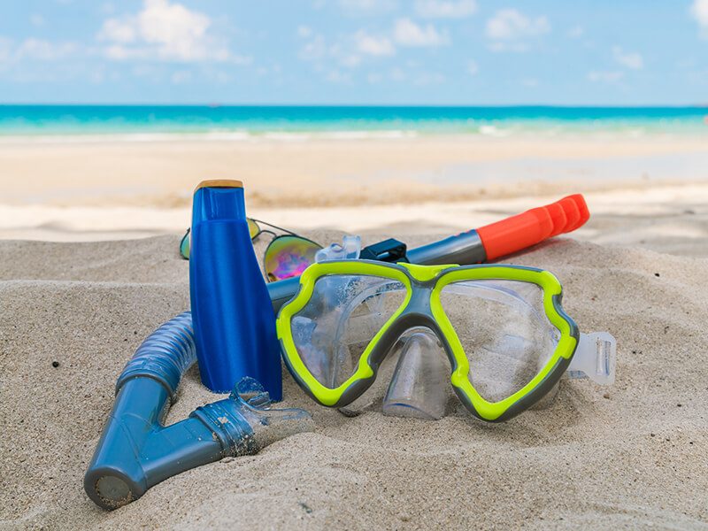 Un masque et un tuba de snorkeling posés sur le sable