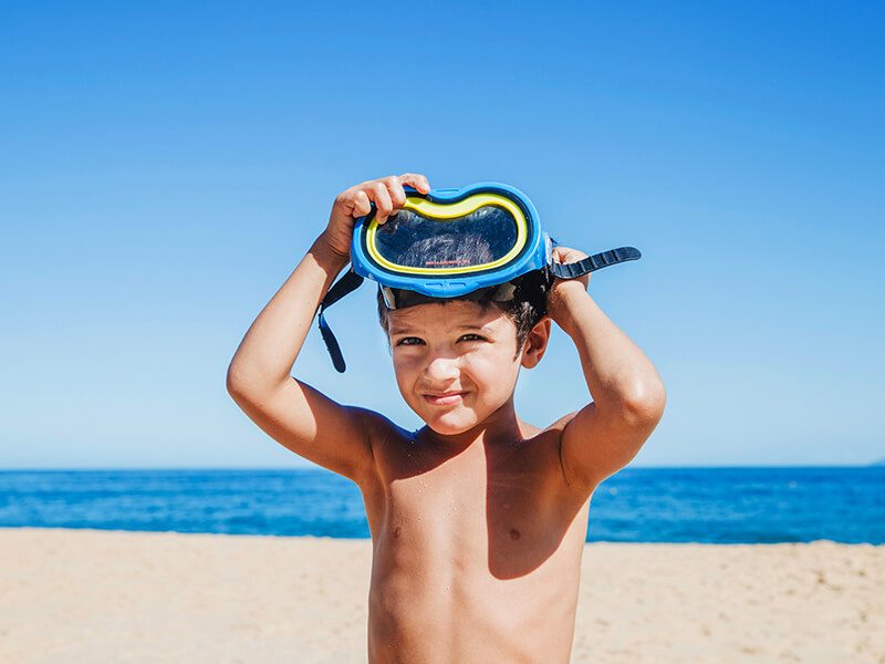 Un jeune enfant sur la plage avec un masque de snorkeling sur le front