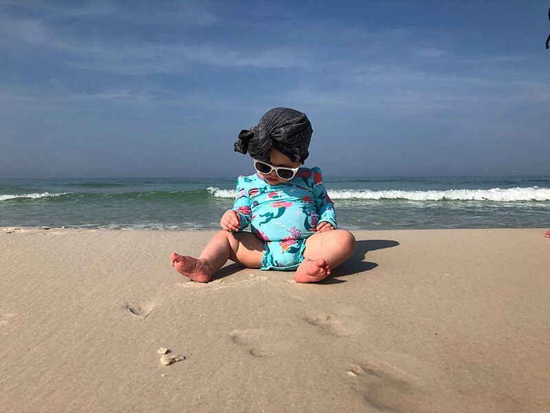 Un bébé assis sur le sable à la plage