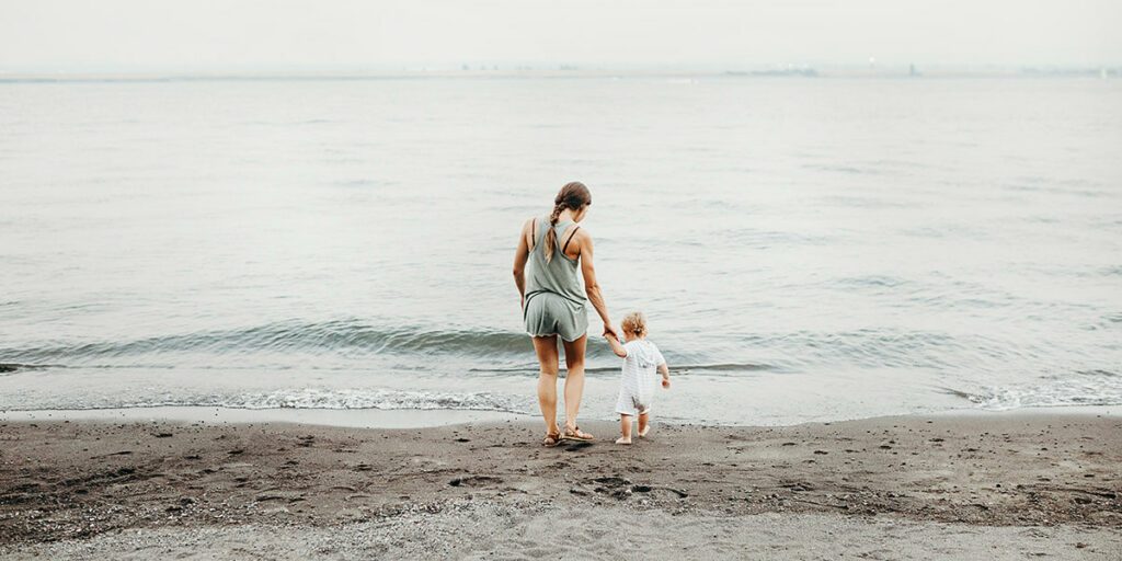 Securite baignade bebe : une maman et son enfant qui se promènent au bord de la mer