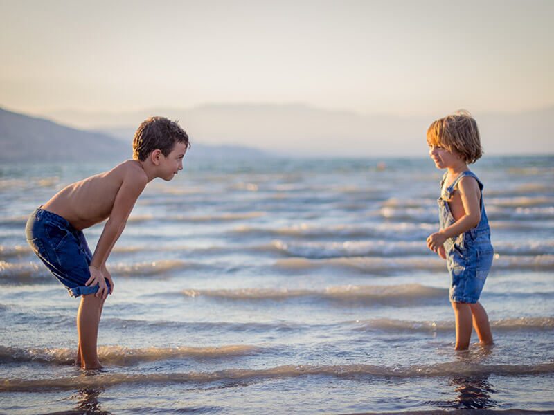 Deux enfants les pieds dans l'eau à la plage