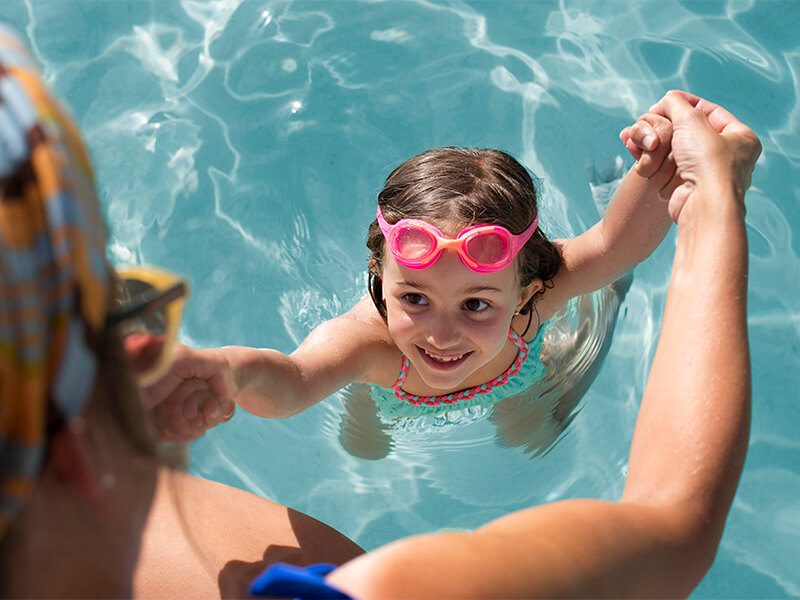 Une maman qui tient sa famille par les bras dans une piscine