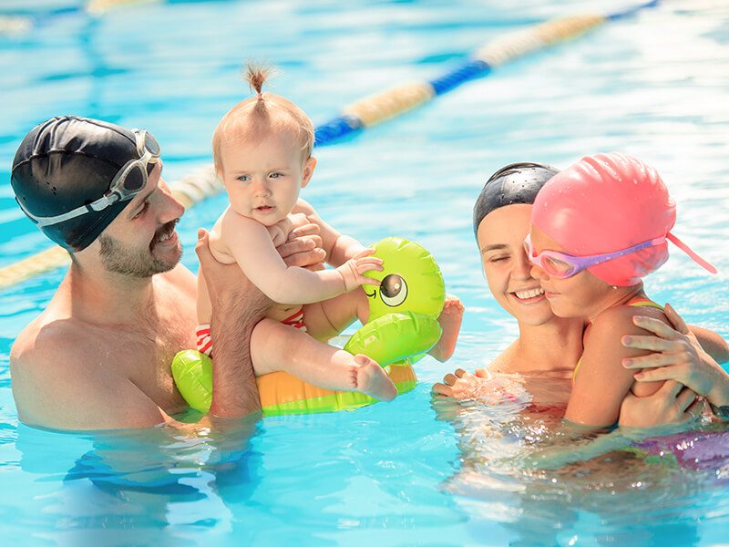 Deux parents avec leurs enfants pendant une séance bébé nageur