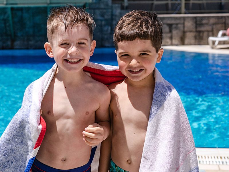 Deux enfants qui sourient au bord d'une piscine