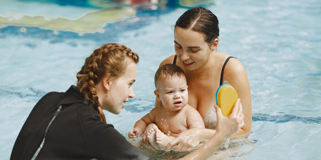 Tenue bebe nageur : une maman et son enfant en cours de bébé nageur avec une maître-nageuse