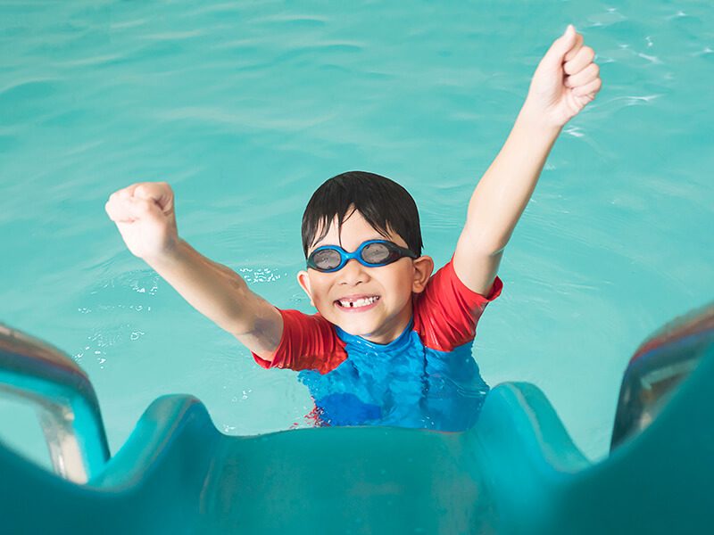 Un enfant souriant dans l'eau d'une piscine