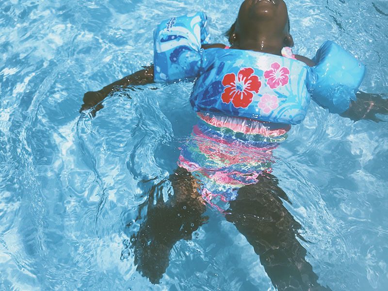 Une enfant qui flotte dans une piscine