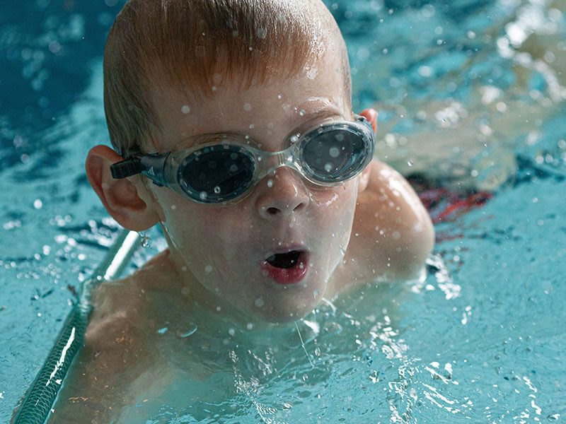 Un enfant avec des lunettes de piscine pendant son cours de natation