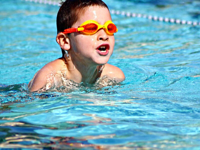 Un enfant qui nage en extérieur pendant son cours de natation