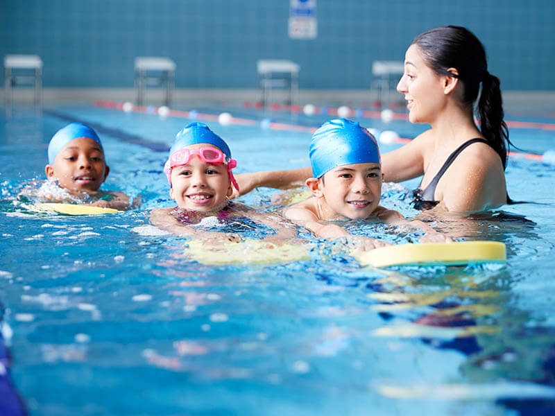 Trois enfants qui suivent un cours de piscine