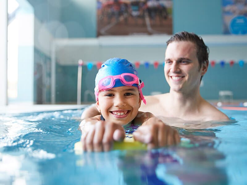 Une petite fille avec son papa à la piscine