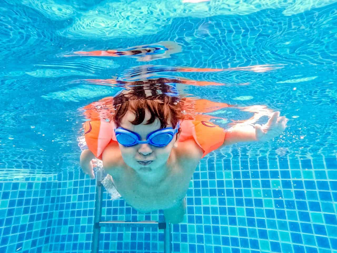 Brassard ou bouée pour bébé : un bébé avec des brassards dans une piscine 